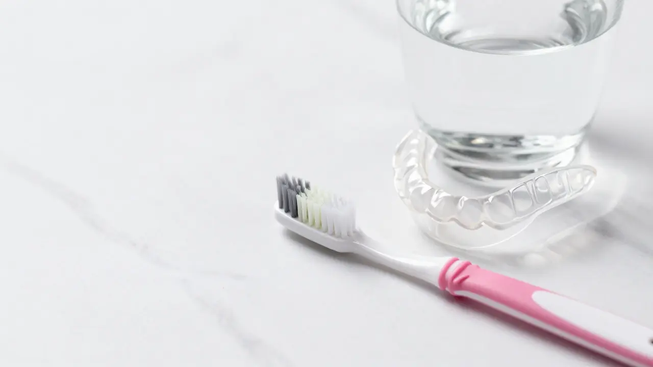 Mezizubní kartáček, zubní kartáč a noční chránič na bílém mramoru.